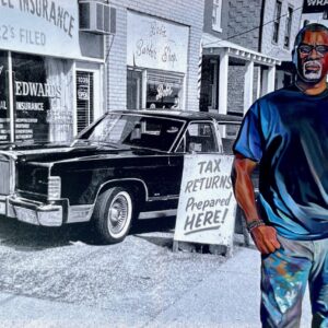 Painting of the artist on exhibit beginning July 9. He is picture in blue jeans and a blue t-shirt. He is a middle aged black male with his thumbs in his pocket looking directly at the viewer. In the background is a black and white painting of an old car.