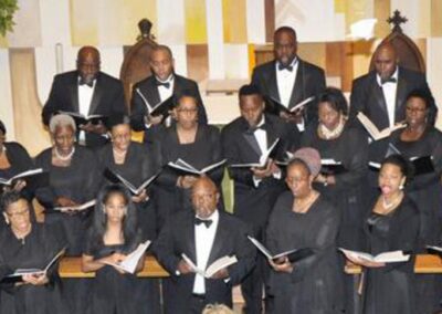 Choir singing in the church in black dresses and suits. The men art wearing black ties and white shirts.