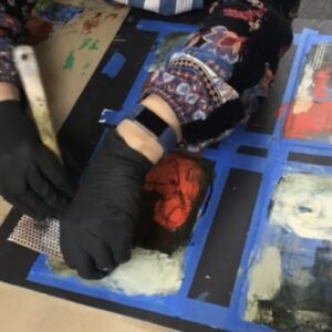 Hands extend and work on cold wax